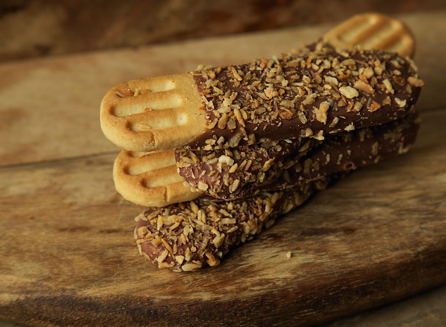 Delicious chocolate-dipped biscotti topped with nuts, perfect for snacks.